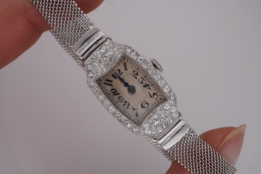 A lady's mid 20th century Swiss white metal(platinum mark) and diamond set cocktail watch with 'tumbling' Arabic numeral dial, on a 9ct white metal mesh link bracelet, case diameter 16mm, overall length 16cm, gross weigh